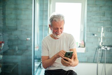 smiling senior man using smartphone in the bathroom